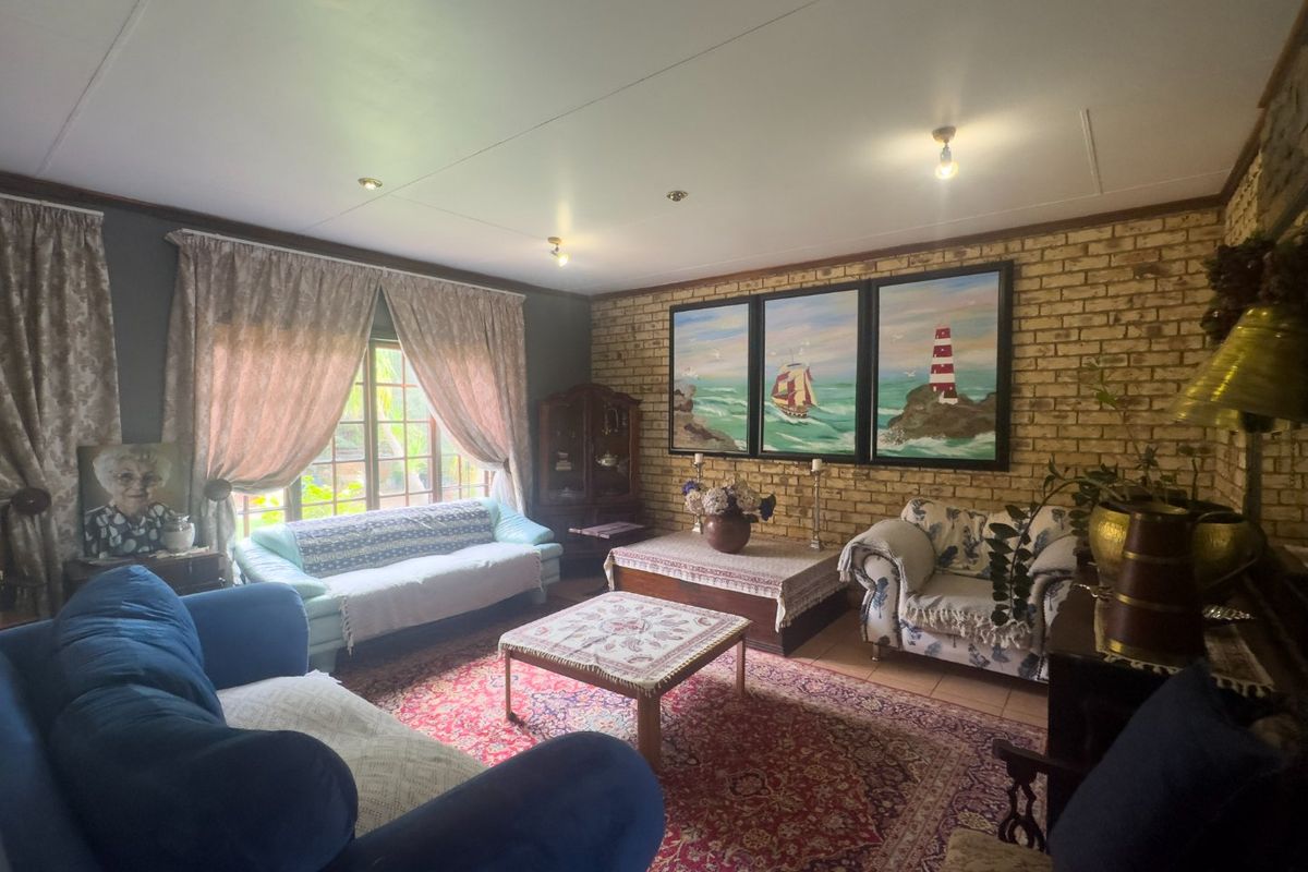 A cozy living room featuring an exposed brick feature wall, tiled flooring, and recessed downlighting, offering a warm and traditional atmosphere.
