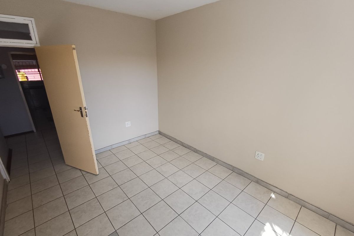 An empty bedroom featuring neutral wall paint and tiled flooring, providing a blank canvas for personalization.