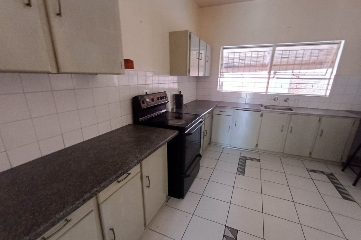 A dated kitchen featuring laminate countertops, tiled backsplash, and original cabinetry. The space is functional but would benefit from modern updates and cosmetic renovation.