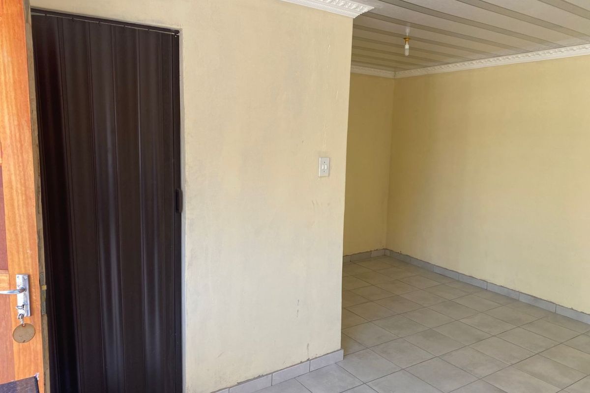 An empty living area featuring tiled flooring, crown molding, and a dark accordion door, providing a blank canvas for interior design.