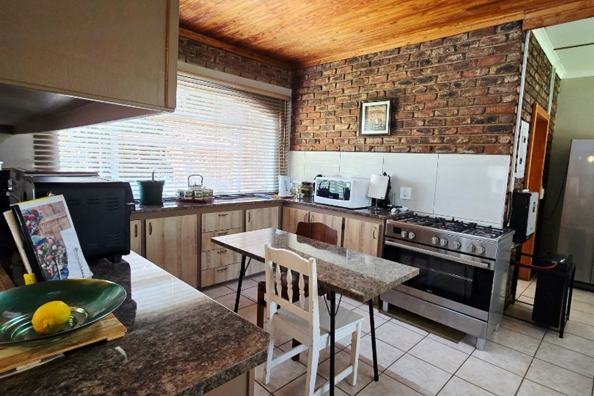 A rustic kitchen featuring exposed brick walls, a timber ceiling, tiled flooring, and a gas stove with ample counter space.