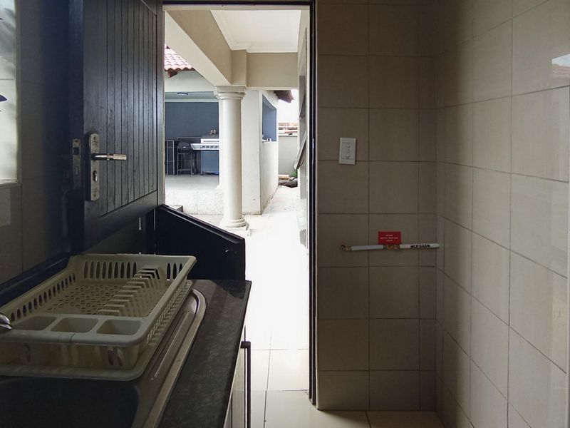 A functional scullery area featuring tiled walls, a stainless steel sink, and a dedicated gas supply point, with direct access to an outdoor patio.
