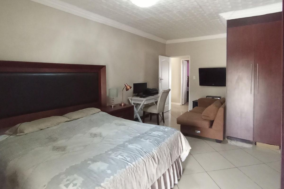 Spacious bedroom featuring tiled flooring, a built-in wardrobe, and a textured ceiling with decorative cornice detailing.