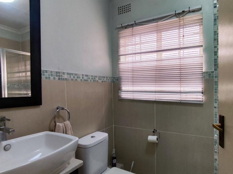 A functional bathroom featuring a modern vessel sink, chrome fixtures, and neutral wall tiling with a decorative mosaic accent border.