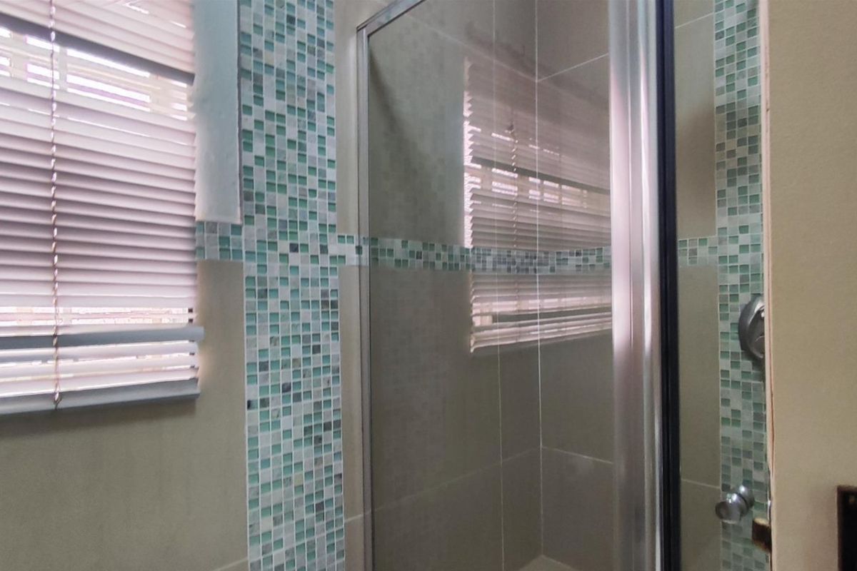 A bathroom shower area featuring a glass enclosure and decorative mosaic tile accents.