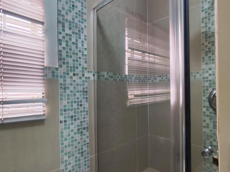 A bathroom shower area featuring a glass enclosure and decorative mosaic tile accents.