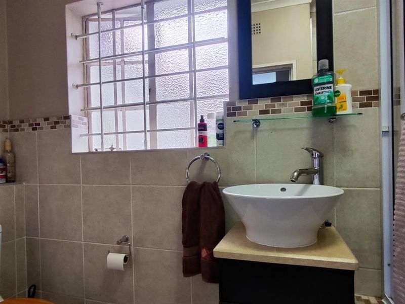 A functional bathroom featuring a vessel sink vanity, tiled walls, a toilet, and a shower enclosure with a frosted window.