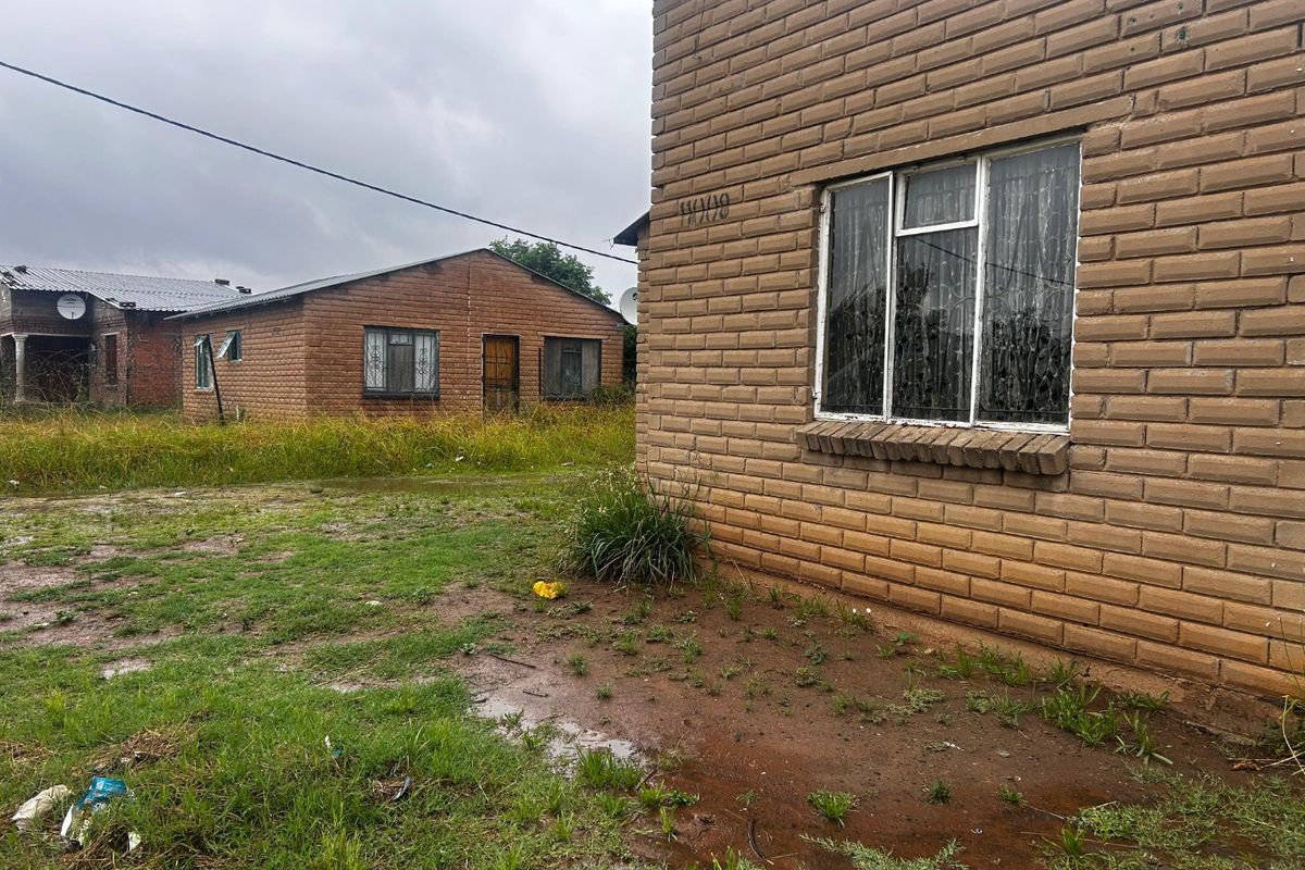 Exterior view of a face brick residential property with surrounding yard space and neighbouring structures.
