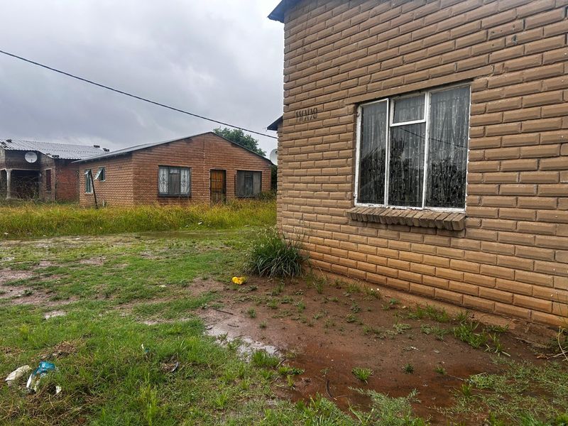 Exterior view of a face brick residential property with surrounding yard space and neighbouring structures.