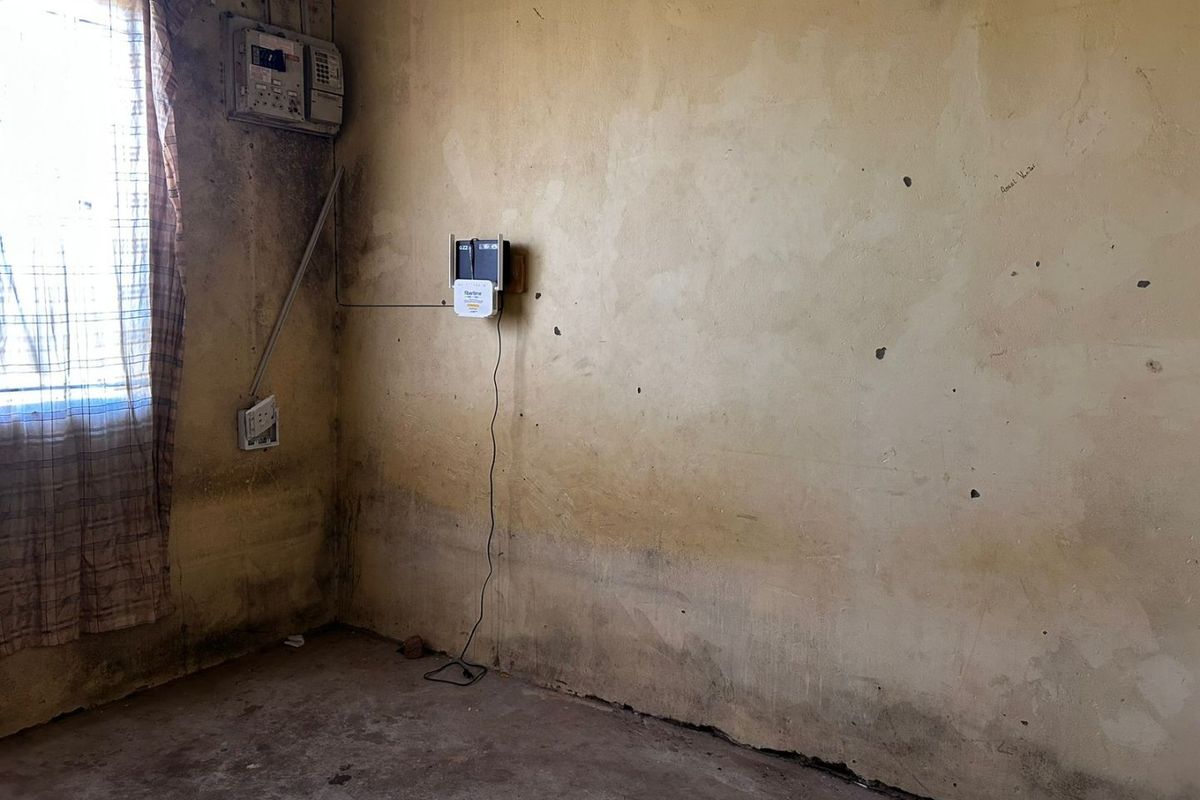 An empty room featuring significant wall damage, staining, and exposed electrical infrastructure, requiring extensive renovation and cosmetic repairs.