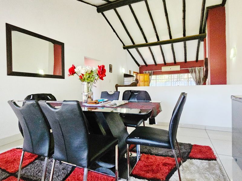 Dining area featuring exposed timber ceiling beams, tiled flooring, and a split-system air conditioning unit.