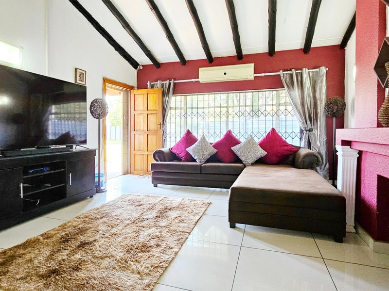 Living room featuring exposed timber ceiling beams, tiled flooring, a built-in fireplace, and a wall-mounted air conditioning unit.