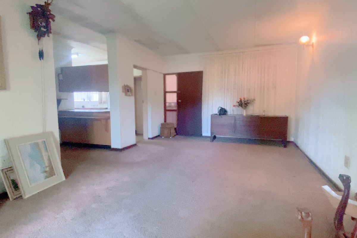 Spacious living area featuring carpet flooring and wall lighting, with an open transition to the kitchen area.