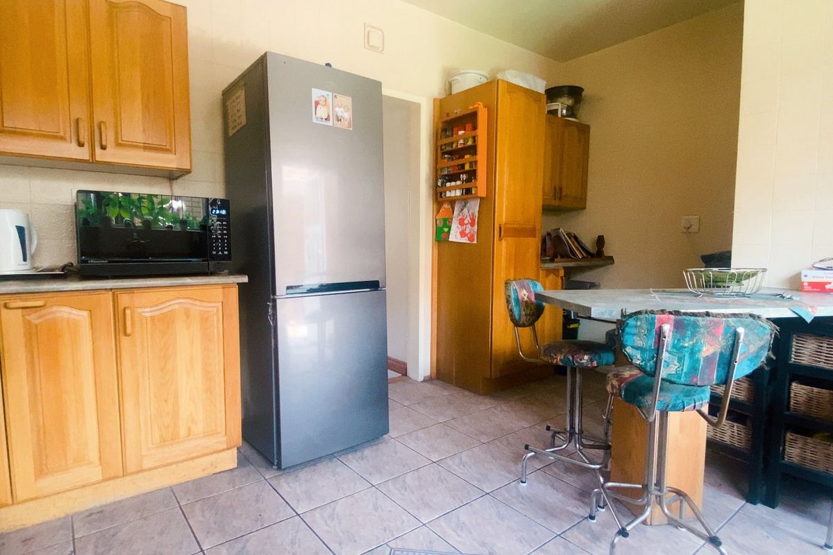 A functional kitchen featuring wooden cabinetry, tiled flooring, and a breakfast nook area, offering a traditional layout with ample storage space.