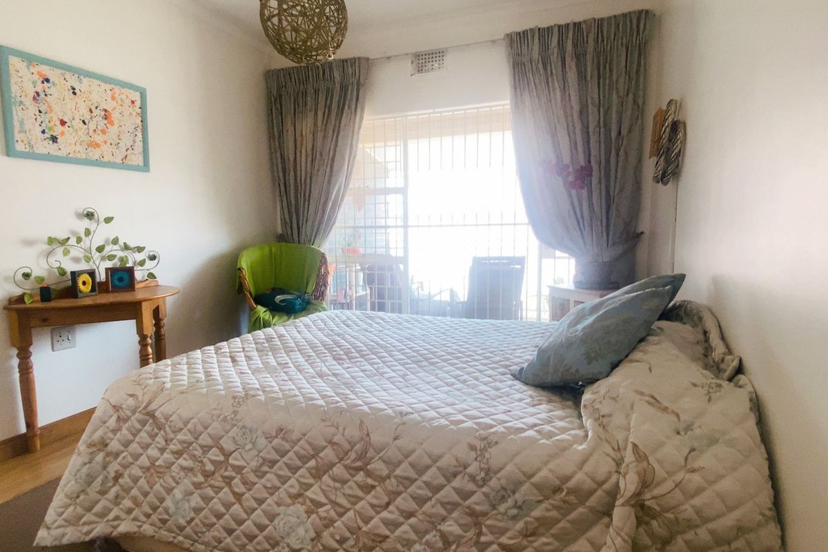 A bedroom featuring a sliding door with security gate access to an outdoor area, neutral walls, and standard finishes.