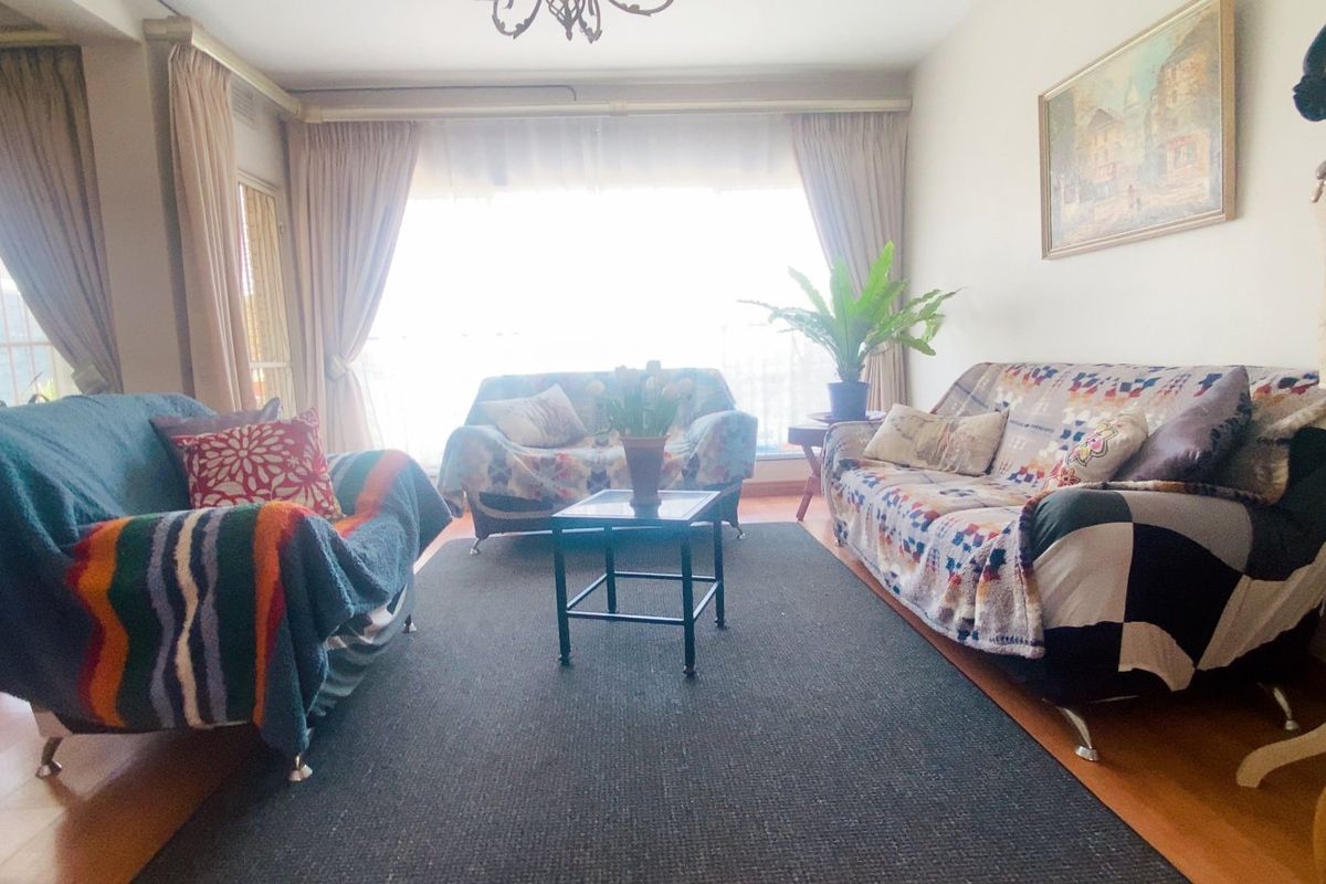 A living room featuring laminate flooring and a large window that allows for natural light.