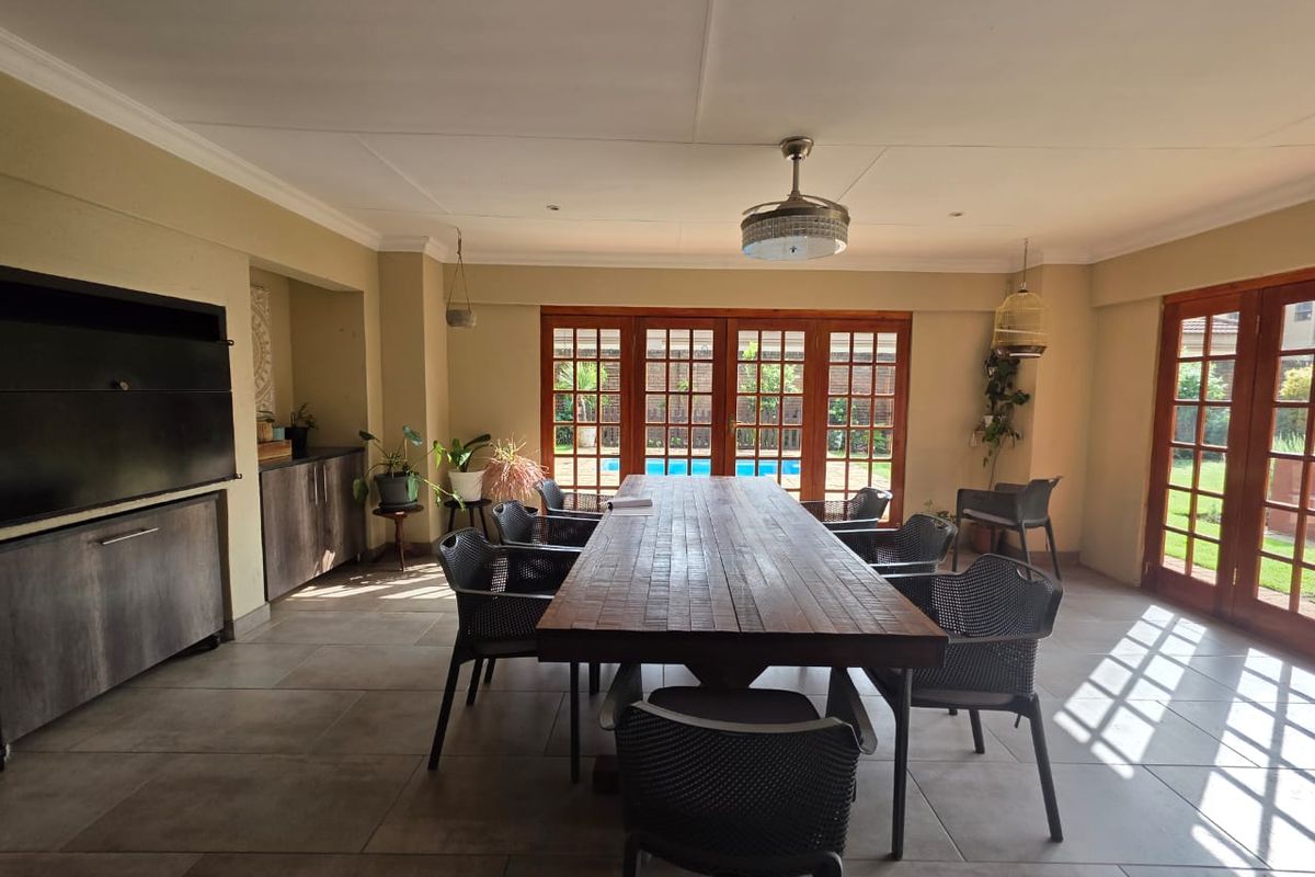 Spacious living area featuring tiled floors, built-in cabinetry, a fireplace, and multiple sets of wooden french doors providing access to the outdoor pool area.