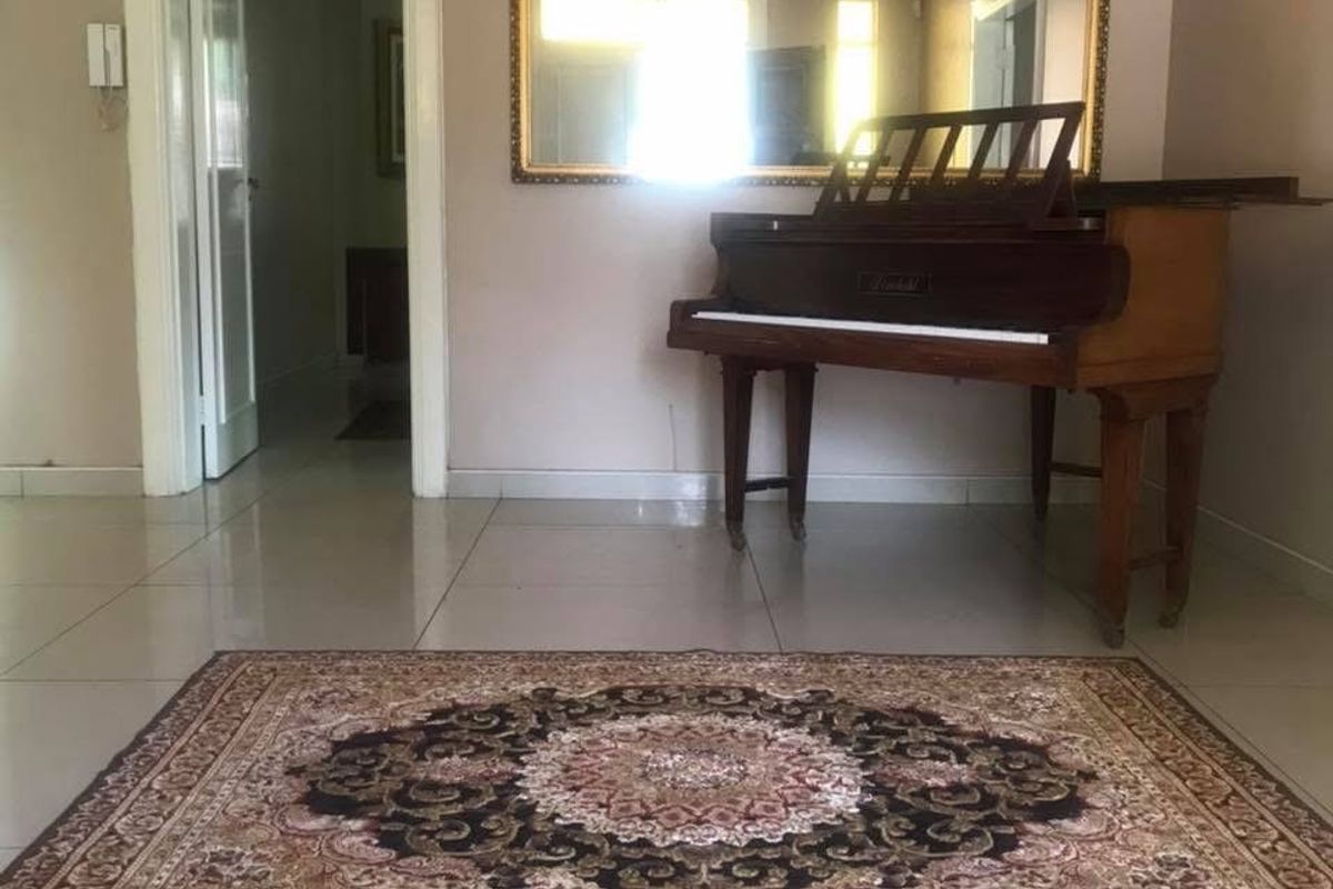 A spacious living area featuring neutral tiled flooring, a doorway leading to an adjacent room, and a large wall-mounted mirror.