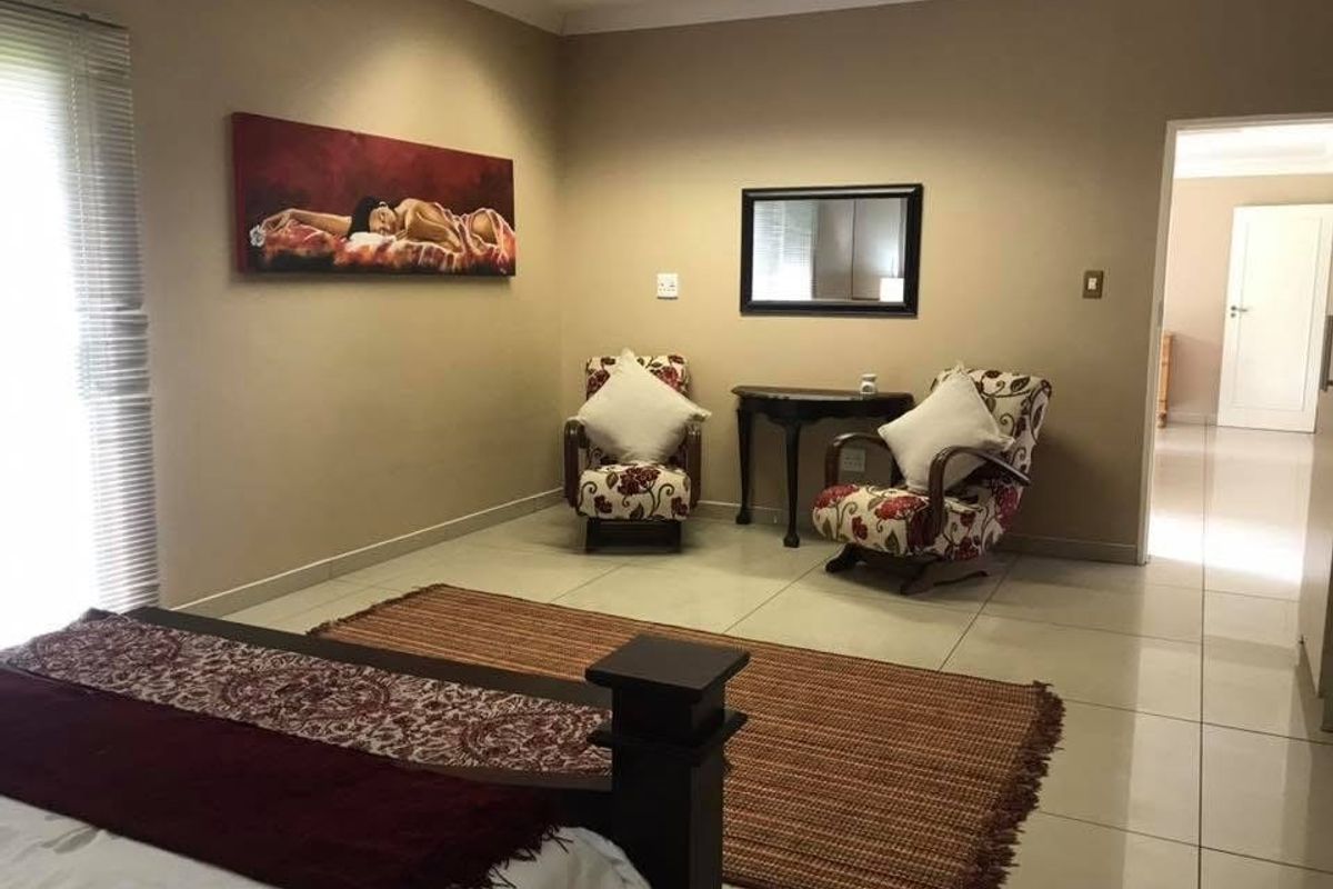 Spacious bedroom featuring neutral tiled flooring, recessed ceiling lighting, and a doorway leading to an adjoining area.