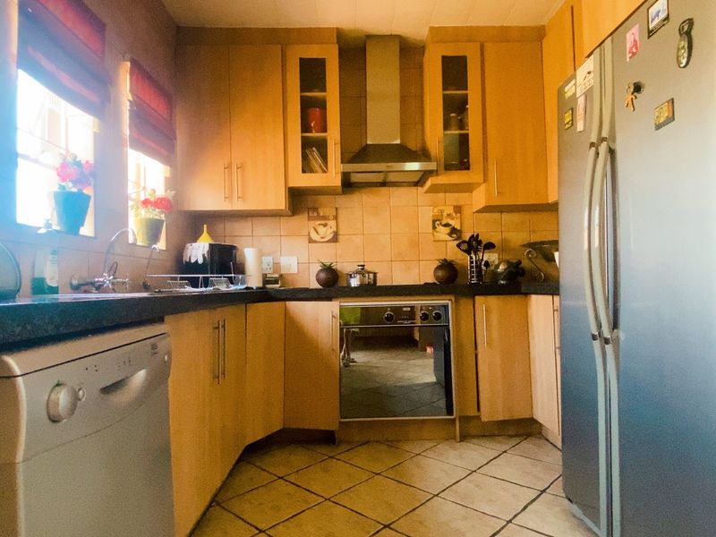 A functional kitchen featuring wooden cabinetry, stone countertops, tiled backsplash, and built-in oven with extractor fan.