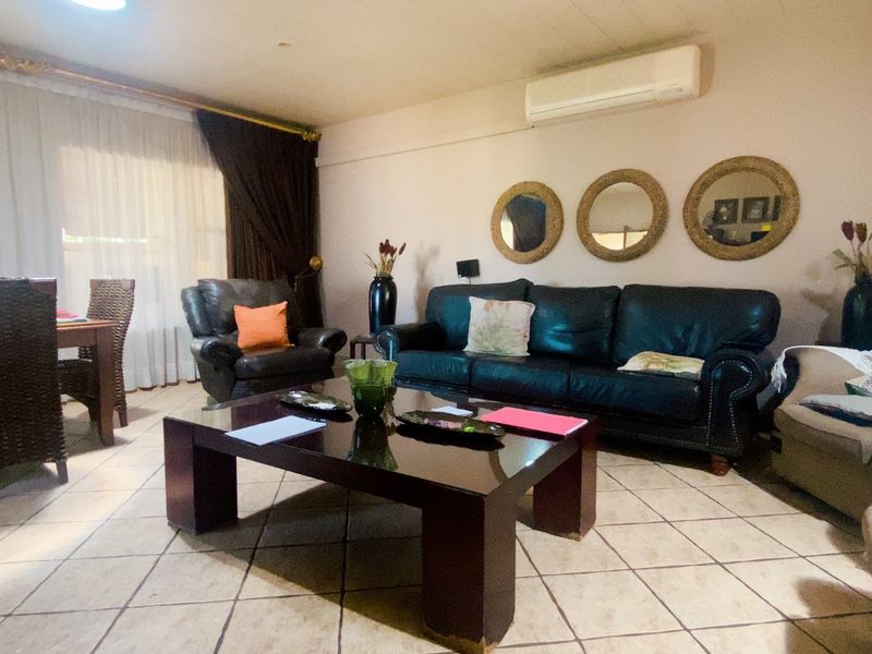 Open-plan living and dining area featuring tiled flooring and a wall-mounted split-system air conditioner.