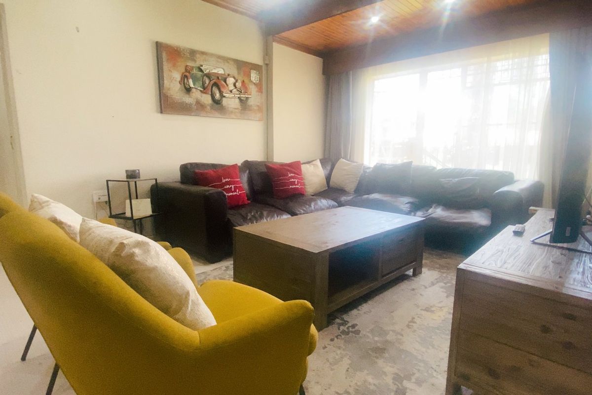 A comfortable living room featuring a warm timber ceiling, recessed lighting, and tiled flooring, providing a cozy space for relaxation.