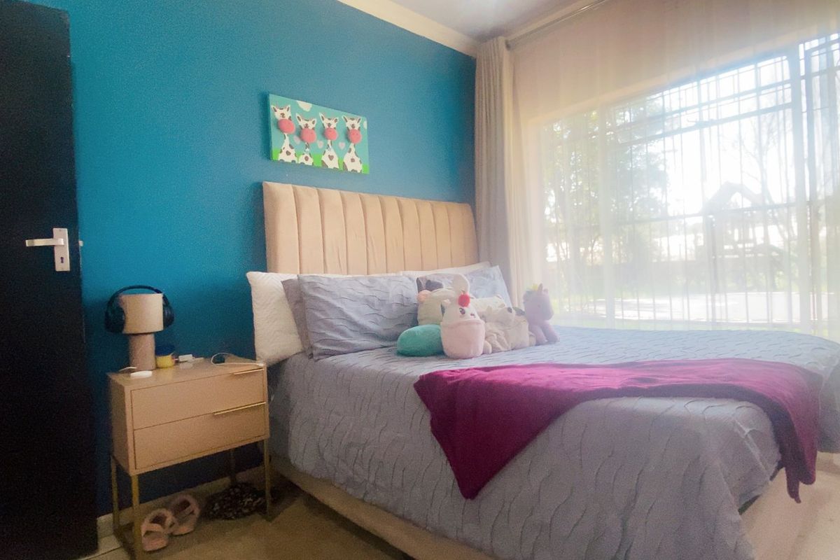 A bedroom featuring a large window with security bars and neutral flooring, providing a functional space with natural light.