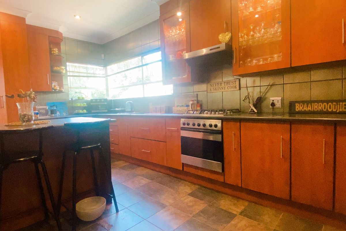 A functional kitchen featuring warm-toned built-in cabinetry, a gas hob with extractor, tiled backsplash, and a convenient breakfast counter for casual dining.