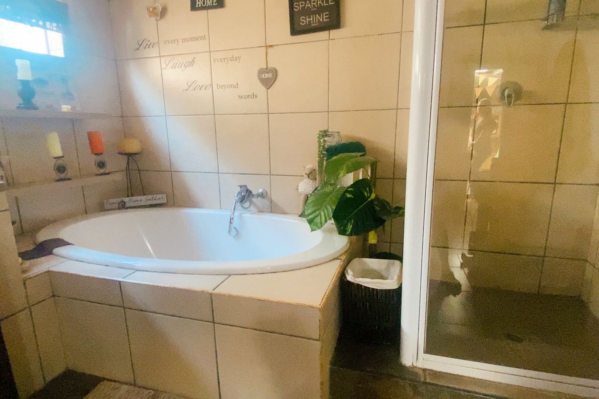 A functional bathroom featuring a built-in bathtub and a separate shower enclosure with tiled finishes throughout.