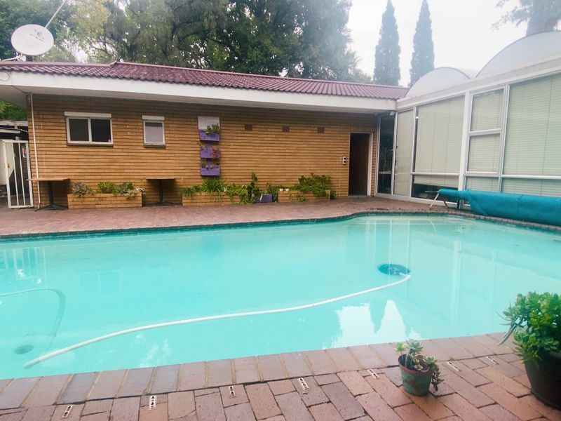 Outdoor pool area featuring a swimming pool, brick paving, and a brick-clad building exterior with large glass sliding doors.