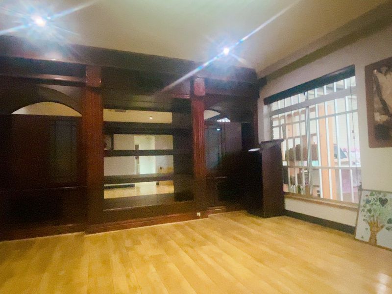 Spacious living area featuring a large built-in wooden shelving unit, recessed lighting, and laminate flooring.