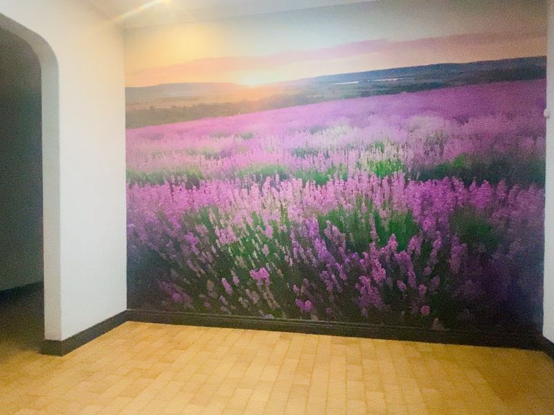An empty living area featuring tiled flooring, an arched entryway, and a large landscape wall mural.