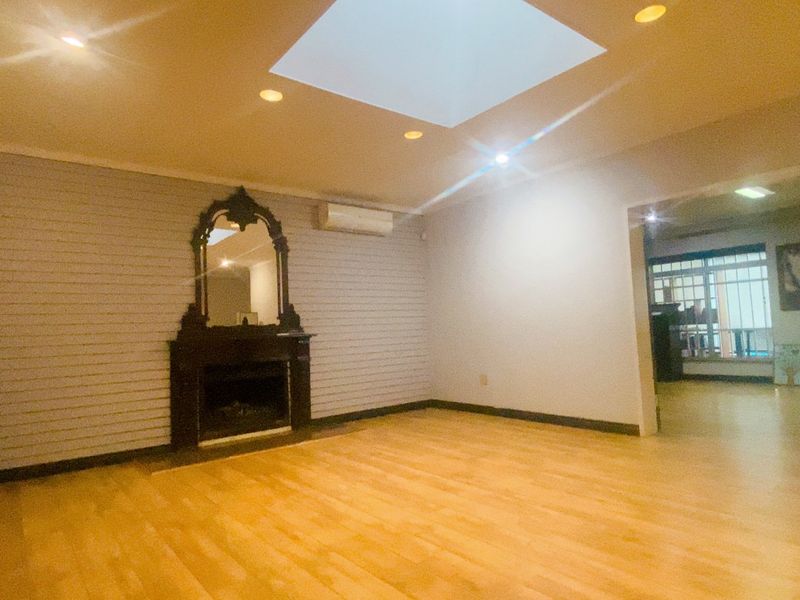 Spacious living room featuring a fireplace, skylight, and split-system air conditioning, offering a bright and open layout with laminate flooring.