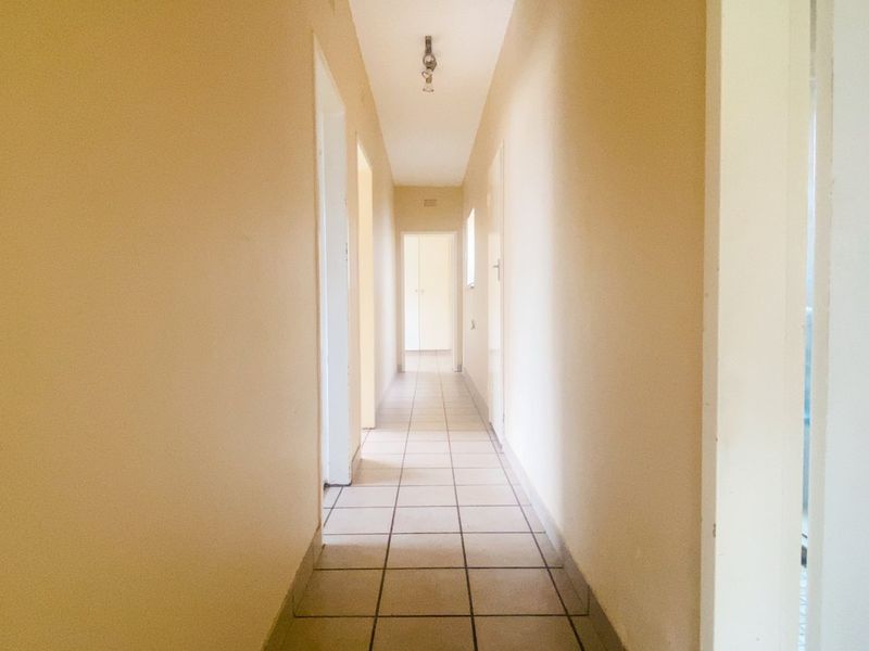 A functional interior hallway featuring tiled flooring and multiple doorways leading to various rooms within the apartment.