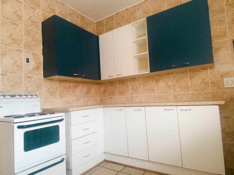 A functional kitchen featuring two-tone cabinetry, tiled walls, and a freestanding stove.