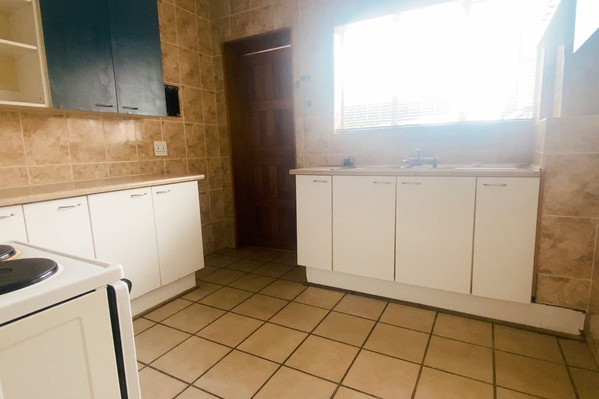 A functional kitchen featuring tiled walls and flooring, built-in cabinetry, and a freestanding stove, offering a practical layout for daily meal preparation.