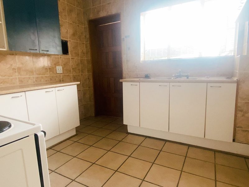 A functional kitchen featuring tiled walls and flooring, built-in cabinetry, and a freestanding stove, offering a practical layout for daily meal preparation.