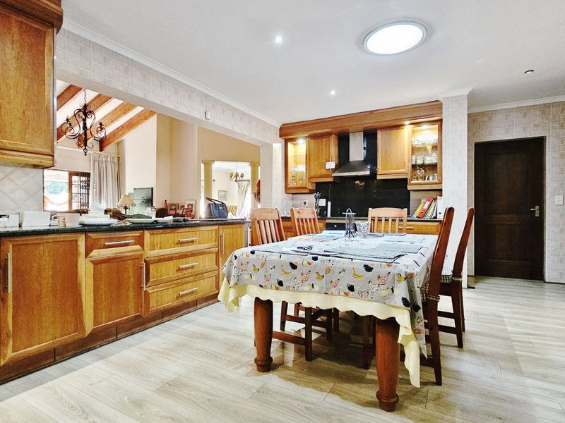 Open-plan kitchen and dining area featuring traditional wooden cabinetry, granite countertops, and a skylight, providing a functional and connected living space.