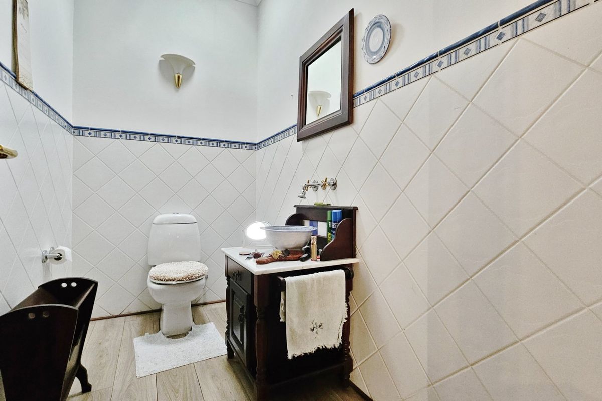 A compact bathroom featuring a classic vanity with a basin, a toilet, and decorative wall tiling with a border accent.