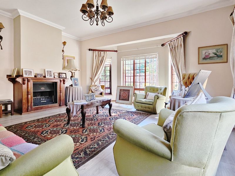 Spacious living room featuring a traditional wooden fireplace mantel, laminate flooring, and large windows allowing for ample natural light.