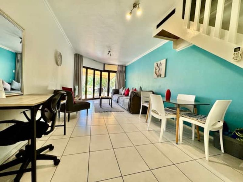 Open plan living and dining area featuring tiled flooring, a staircase, and sliding glass doors leading to an outdoor space.