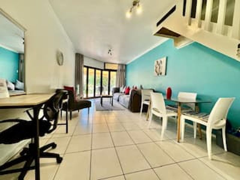 Open plan living and dining area featuring tiled flooring, a staircase, and large sliding glass doors leading to an outdoor space.