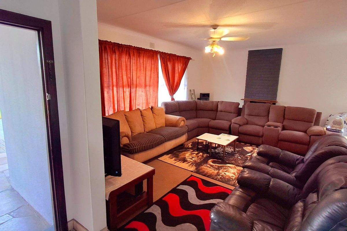 Spacious living room featuring a brick fireplace surround, ceiling fan, and direct access to an outdoor patio area.