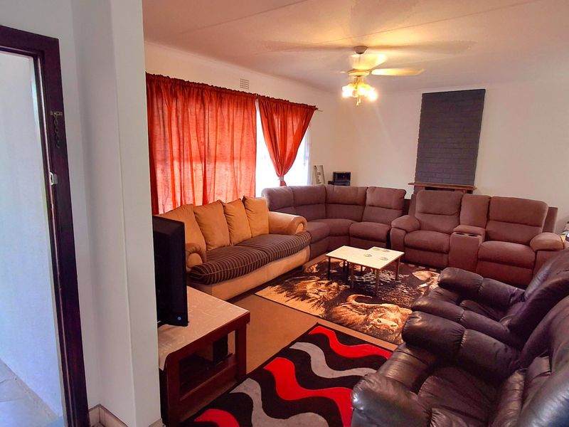 Spacious living room featuring a brick fireplace surround, ceiling fan, and direct access to an outdoor patio area.