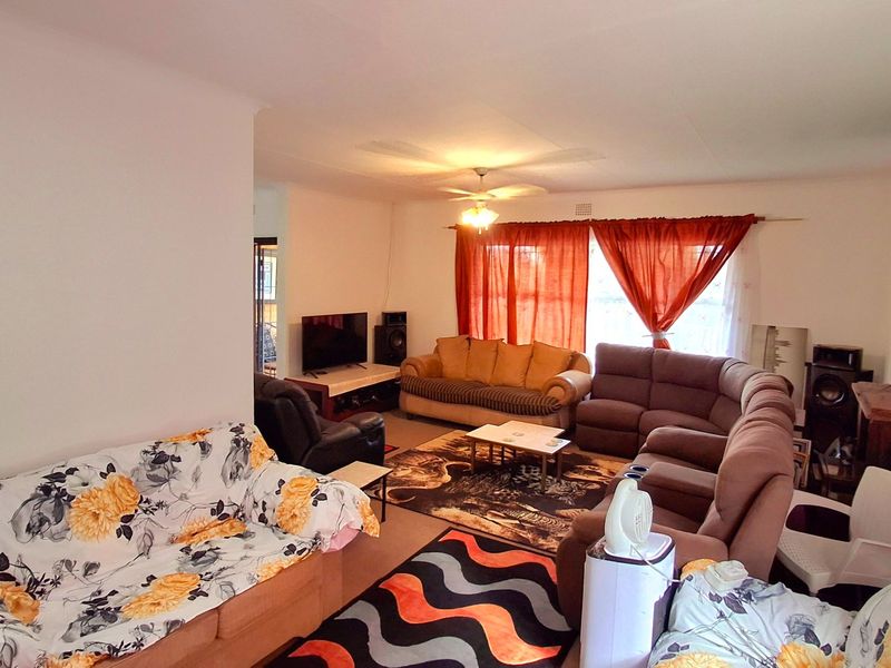 Spacious living room featuring a ceiling fan and a brick fireplace, offering a comfortable area for relaxation and family gatherings.