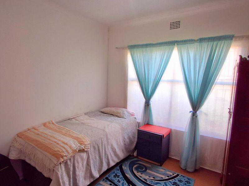 A standard bedroom featuring a window with a curtain rail and a built-in ventilation grille.