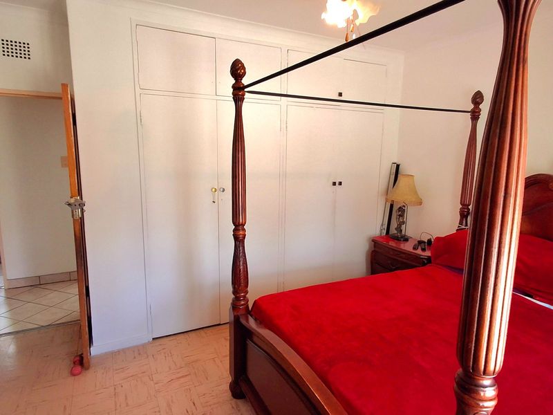 A bedroom featuring built-in cupboards, tiled flooring, and an adjoining bathroom entrance.