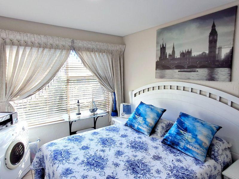 A bedroom featuring a window with venetian blinds and curtain tracks, providing natural light and a functional layout.