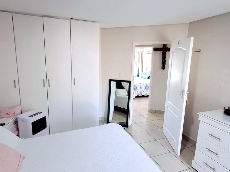 A bedroom featuring built-in cupboards and tiled flooring, with an open doorway leading to an adjacent room.