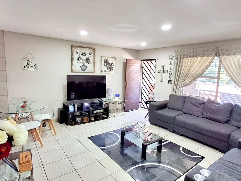 A well-lit living room featuring tiled flooring and recessed downlights, providing a functional and comfortable space for relaxation and daily living.